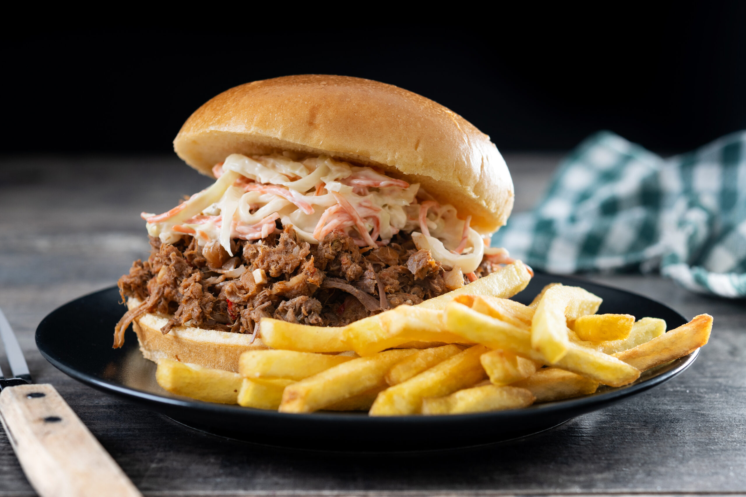 Pulled pork sandwich with coleslaw salad on wooden table